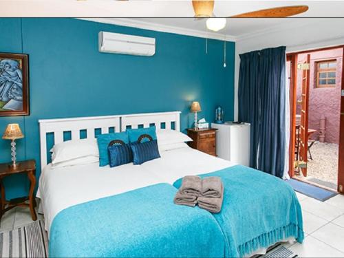 a blue bedroom with a bed with a blue wall at Gumtree Guest House in Oudtshoorn