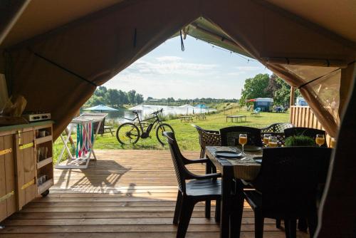 Tienda de campaña con mesa y sillas en una terraza en Camping de Boomgaard, en Maaseik