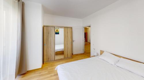 a bedroom with a white bed and a mirror at Serenity Retreats VRT in Sibiu