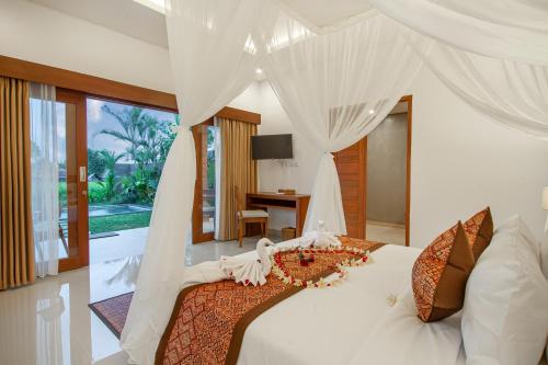 a bedroom with a white bed with a canopy at Palasari Villa in Tegalalang