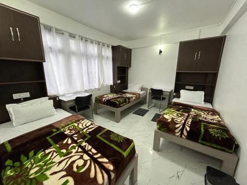 Habitación con 2 camas y sillas. en Addy's Inn en Gangtok