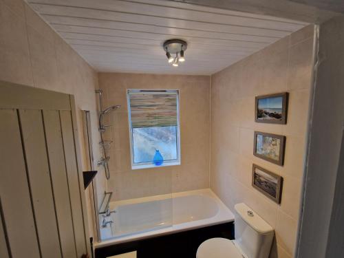 a bathroom with a tub and a toilet and a window at Coopers Cottage in Peterhead