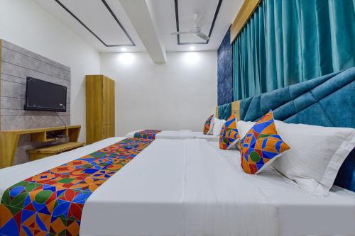 アーメダバードにあるHOTEL GREEN TREEのベッドルーム(大きな白いベッド、カラフルな枕付)