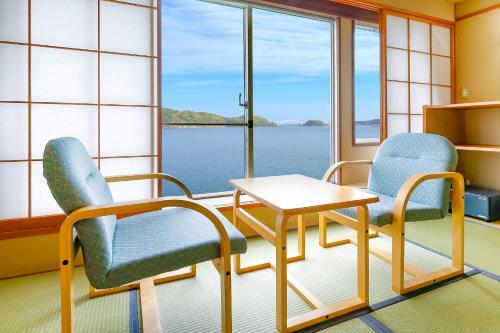 a room with two chairs and a table and a window at Ooedo Onsen Monogatari Nanki Kushimoto in Kushimoto