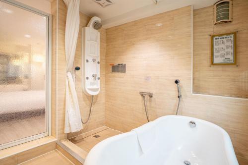 Guide Hotel Kaohsiung Shinkuchan في كاوشيونغ: حمام مع حوض استحمام ودش