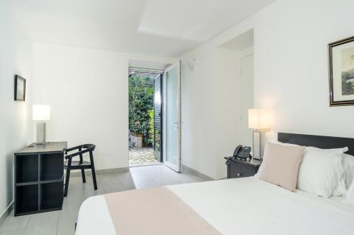 a white bedroom with a large bed and a desk at Residence Le Axidie in Vico Equense