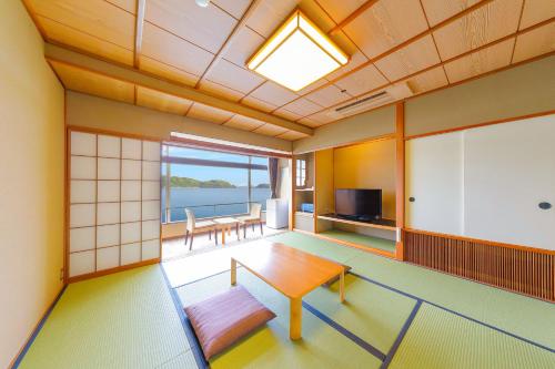 a room with a table and a view of the ocean at Ooedo Onsen Monogatari Nanki Kushimoto in Kushimoto