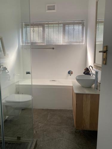 uma casa de banho com um chuveiro, um WC e um lavatório. em Churchill Cottage em Gillitts