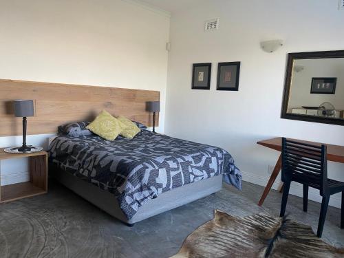 een slaapkamer met een bed, een bureau en een spiegel bij Churchill Cottage in Gillitts