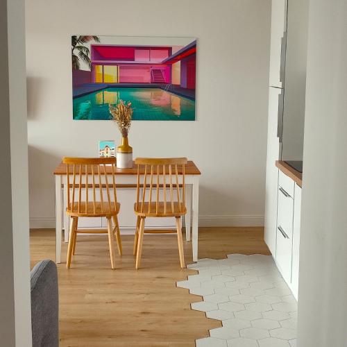 a dining room table with two chairs and a painting on the wall at Appart hôtel & Spa La Villa du Port in Vannes