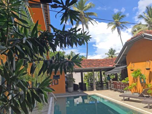 a house with a swimming pool and palm trees at Suite Lanka in Hikkaduwa