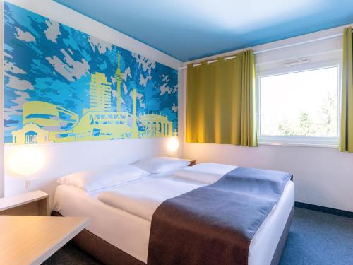 ein Hotelzimmer mit einem Bett und einem großen Fenster in der Unterkunft B&B Hotel Stuttgart-City in Stuttgart