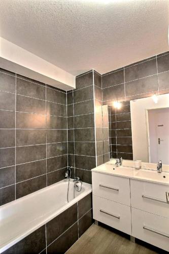 une salle de bain avec une baignoire, un lavabo et un miroir dans l'établissement Deky, à Sérignan