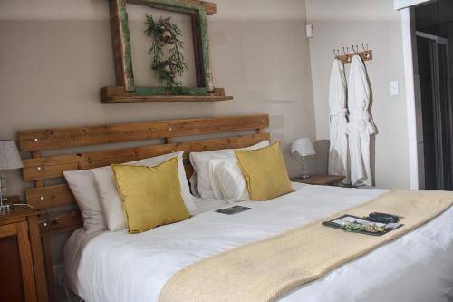 a bedroom with a large white bed with yellow pillows at De Akker Guest House Oudtshoorn in Oudtshoorn