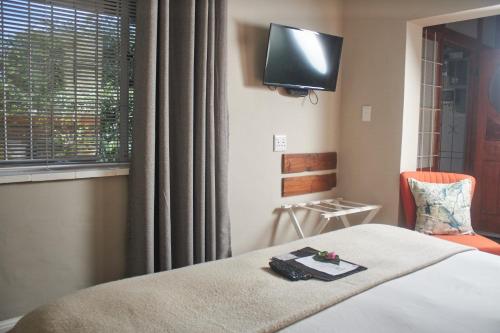a bedroom with a bed with a tv on the wall at De Akker Guest House Oudtshoorn in Oudtshoorn