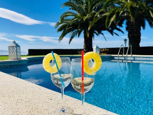 dos copas de vino sentadas junto a una piscina en Villa en una isla con piscina privada!, en La Matanza de Acentejo