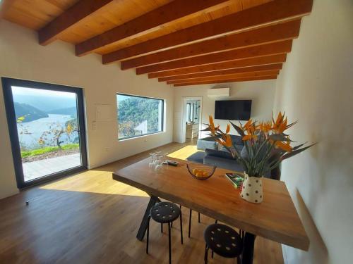 a living room with a wooden table and a large window at Quinta Vale do Cabo in Riba Douro