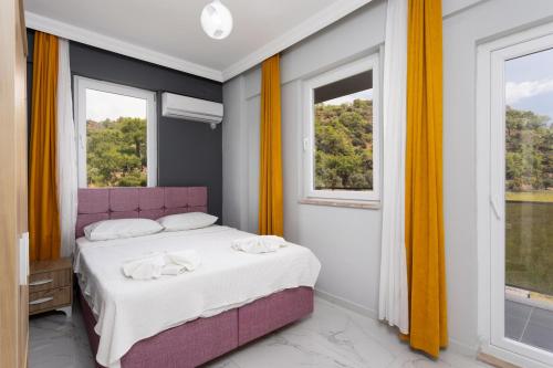 a bedroom with a purple bed and two windows at Villa Sasha 2 in Ortaca