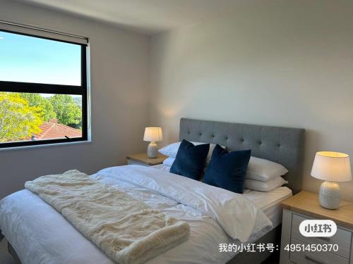 Un dormitorio con una cama con almohadas azules y una ventana en Northshore Charming 4 bedrooms, en Auckland