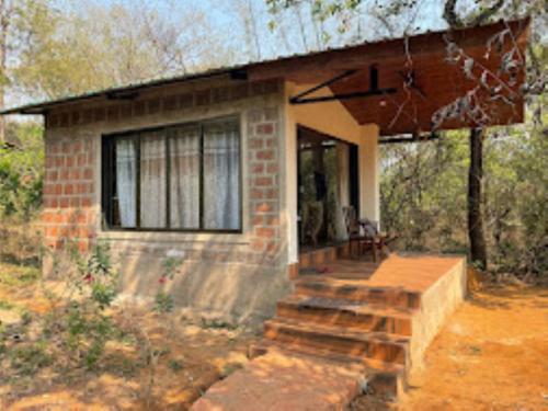 a small brick house with a porch and a window at Vanoshi Forest Homestay,Kudase in Maneri