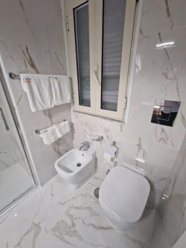 a white bathroom with a toilet and a sink at Hotel Caribe in Casalnuovo di Napoli