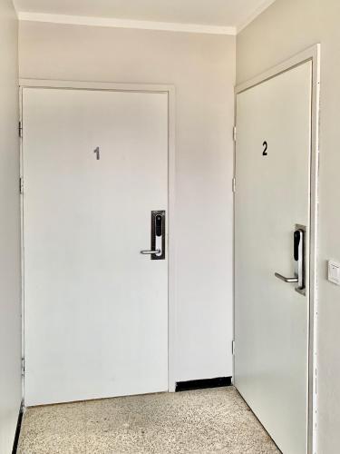 two white doors in a white room with numbers on them at Teurastamo: Ylivieskan upea Helmi 1 in Ylivieska