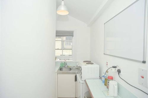 cocina blanca con fregadero y ventana en SOHO Flat (Central London), en Londres