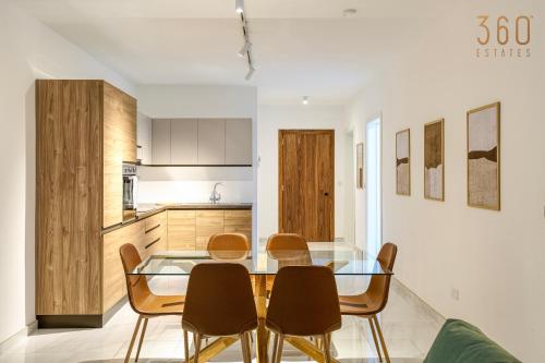 een keuken en eetkamer met een glazen tafel en stoelen bij Modern 2BR Apt with Private Terrace & Sofa Bed by 360 Estates in St Paul's Bay