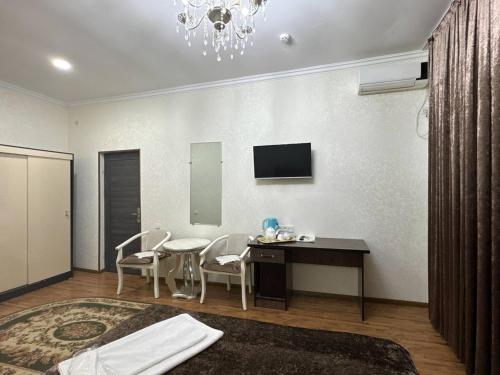 a room with a table and chairs and a television at RATMINA HOTEL in Nukus