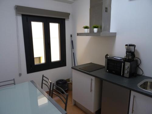 a kitchen with a counter with a microwave and a window at Center Plaza Figueres in Figueres