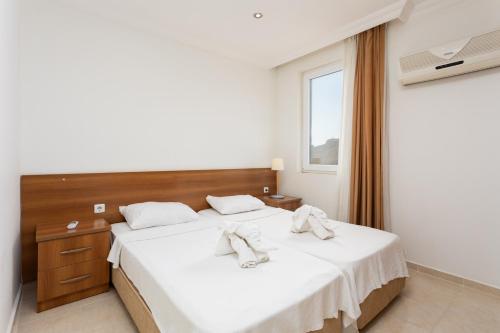 a bedroom with a bed with white sheets and a window at Villa Oliv in Oludeniz
