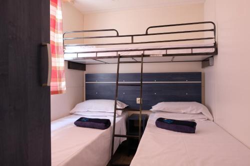 サルキットゥ・クーリエリにあるHappy Camp mobile homes in Camping Village Bella Sardiniaの二段ベッド2組(白いシーツ付)が備わる客室です。