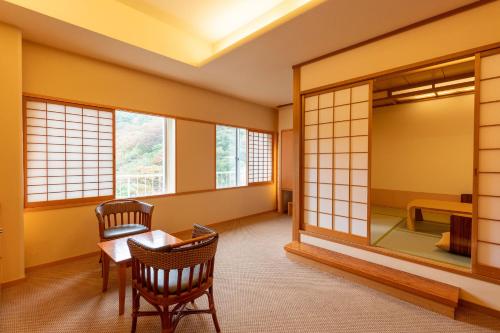 Zimmer mit einem Tisch, Stühlen und einem Spiegel in der Unterkunft Ooedo Onsen Monogatari Higashiyama Grand Hotel in Aizu-Wakamatsu