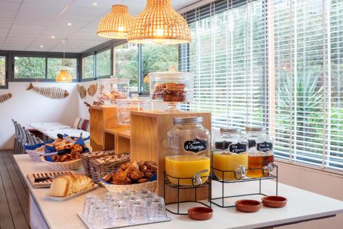 een ontbijttafel met potten sinaasappelsap en brood bij Hotel Residence Les Medes in Porquerolles