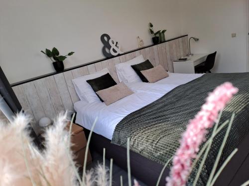 a bedroom with a bed with white sheets and pillows at B&B de Wilhelminaschool in Aalten