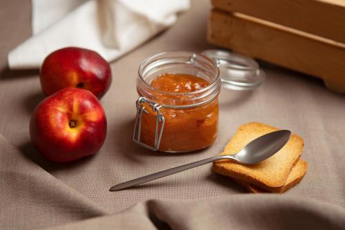 a jar of jam and two apples and a spoon at Rifugio Cereda in Fiera di Primiero
