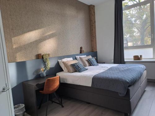 a bedroom with a bed and a desk and a window at B&B de Wilhelminaschool in Aalten
