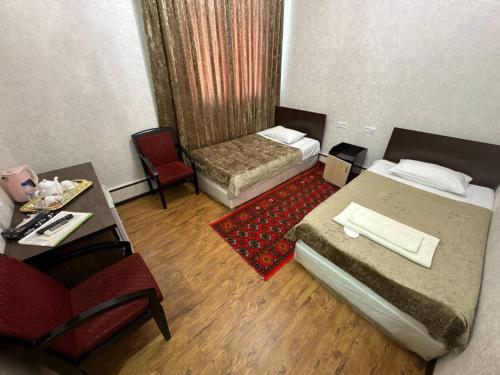 a small room with two beds and a table and chairs at RATMINA HOTEL in Nukus