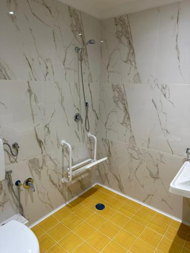 a bathroom with a shower and a yellow tile floor at Hotel Caribe in Casalnuovo di Napoli