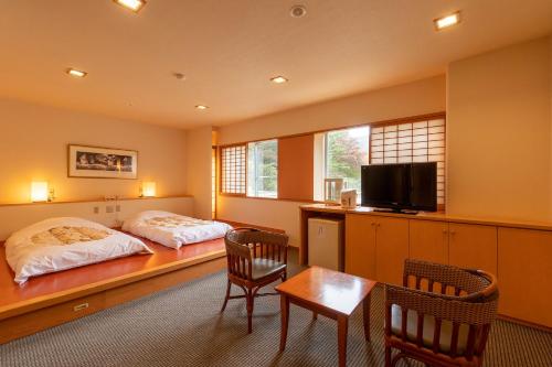 會津若松的住宿－Ooedo Onsen Monogatari Higashiyama Grand Hotel，一间卧室配有两张床和一张桌子及椅子