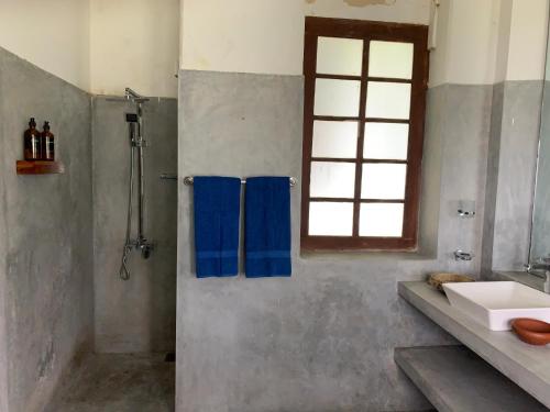 łazienka z prysznicem, umywalką i oknem w obiekcie Stuart House Tangalle w Tangalli