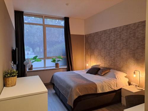 a bedroom with a bed and a large window at B&B de Wilhelminaschool in Aalten