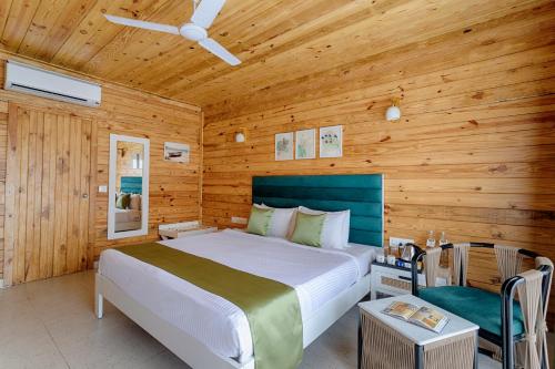 a bedroom with a bed and a wooden wall at Aralea Beach Resort By Stone Wood, Morjim in Morjim