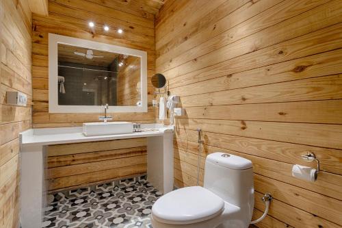a bathroom with wooden walls and a toilet and a sink at Aralea Beach Resort By Stone Wood, Morjim in Morjim