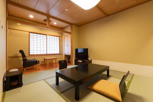 a living room with a table and chairs and a television at Ooedo Onsen Monogatari Higashiyama Grand Hotel in Aizuwakamatsu