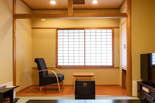 a living room with a chair and a window at Ooedo Onsen Monogatari Higashiyama Grand Hotel in Aizuwakamatsu