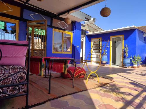 Riad dar sahrawi في مراكش: منزل ملون مع طاولة على الفناء
