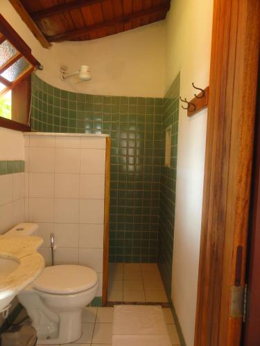 a bathroom with a toilet and a green tiled shower at Pousada Aldeia in Ilha de Boipeba