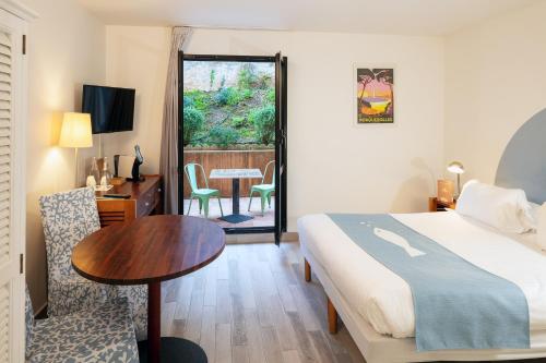 Cette chambre comprend un lit, un bureau et une table. dans l'établissement Hotel Residence Les Medes, à Porquerolles