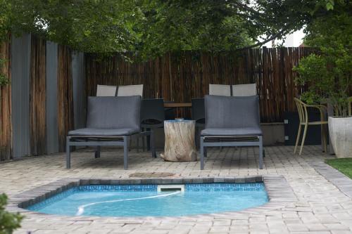 a patio with two chairs and a small pool at De Akker Guest House Oudtshoorn in Oudtshoorn